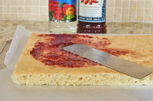 Spread raspberry jam over one layer of almond sponge